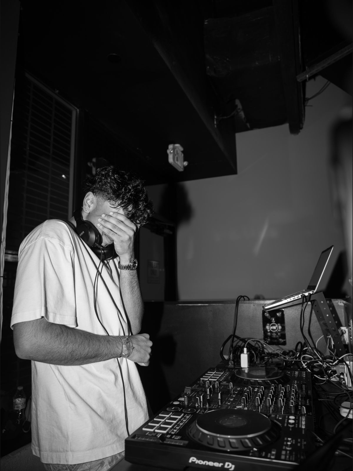 AADIKTIV in the booth with his hand over his face, black and white
