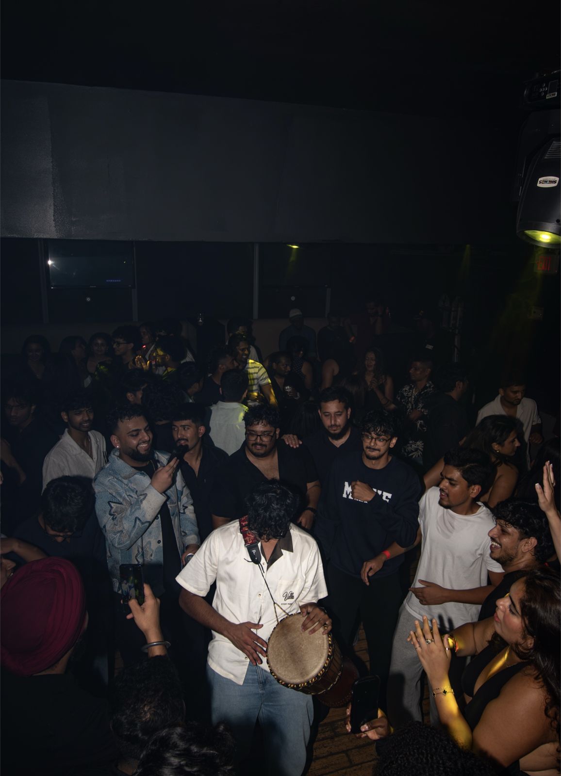 AADIKTIV playing a hand drum in the middle of a packed crowd